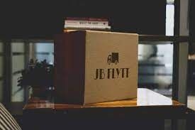 Cardboard box with JB Hi-Fi logo on a table, books in the background.